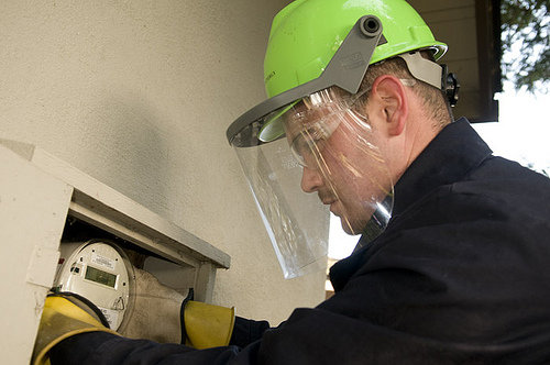 An electricity company worker installs an energy meter