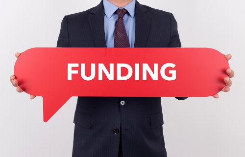 Businessman holding speech bubble with a word FUNDING