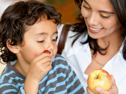 Woman and son at a supermarket eating fruits
