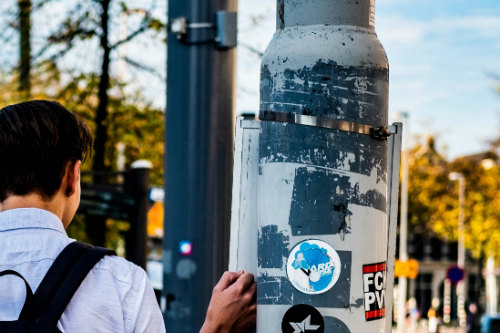 Person sticking sticker on lamp post