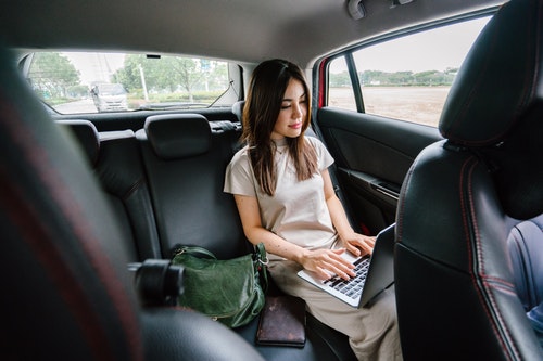 Business woman working on laptop in car